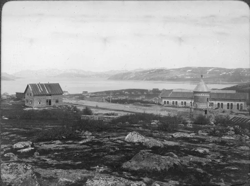 Et hus, mulig banevokterbolig og et vanntårn langs jernbanen til A/S Sydvaranger i Kirkenes. Utsikt over byen og fjorden i bakgrunnen.