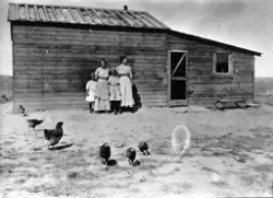 To kvinner og to jenter står foran et en-etasjes hus med påb