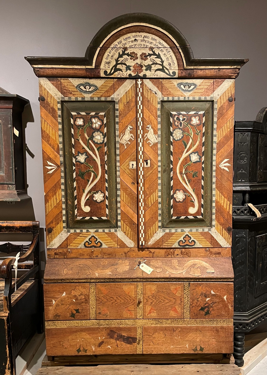 Skänkskåp tillverkat av ek, med inläggningar av ljusare träslag på dörrarna. 
De är smyckade med inläggningsarbeten i ben och pärlemor av bl a. änglar, fabeldjur, 
bladrosetter m.m.. Fyllningarna på dörrarna är starkt utskjutande jämfört med övriga skåpet. 
På det svängda krönet ovanför dörrarna står målat på en ljus bakgrund:
"Hvad adlig ätt et ord som hastighet nämnes. Hvad stora svaghet som i grafwen lemnas. 
Hvad högtvis konst et- af huffved blott. Hvad nit och flit beswär för spe och spott Mos 1806".
Överstycket har en kraftig profilerad krönlist. Dörrarna är också försedda med bladformiga smidda gångjärn. 
I överdelen på skåpet finns fyra hyllor, varav den översta är gjord såsom en skedhylla, kraftigt utsvängd och försedd 
med åtta urtag för skedar. 
Nedre delen på skåpet har tre draglådor också försedda med inläggningsarbete av trä samt målningar. Den översta 
lådan är indragen i överkanten varför den påminner om snedklaff. 
Lådorna har ej de ursprungliga knopparna. Sidorna på skåpet är 
neddragna, de fungerar därför som ben. Dörrarna är försedda med lås. Högerdörren har lås medan vänsterdörren 
har en spärrhake fäst i mitthyllan. 
Nyckelskylten är av ben.