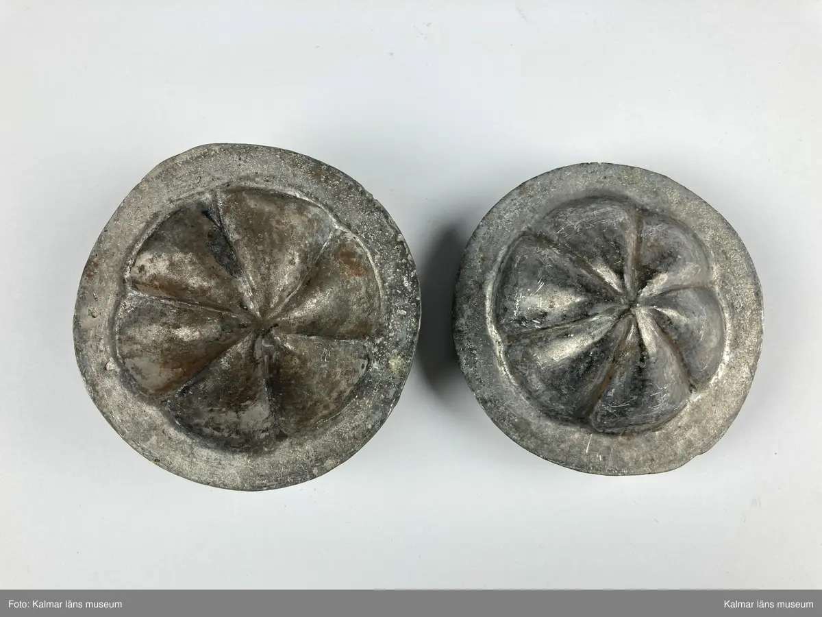 KLM 46890:24. Stans. 2 delar. För tillverkning av kakformar. Av bly. Stansen består av ett ovalt block med försänkning i form en rund kakform med vågigt mönster. Till stansen hör en kontra med kakformens form, denna passar försänkningen på stansen och lägges där i. Materialet som ska pressas läggs mellan stansens båda delar och försetts sedan med tyngd för att forma materialet. Kakform KLM 46890:21 har tillverkats med stansen.