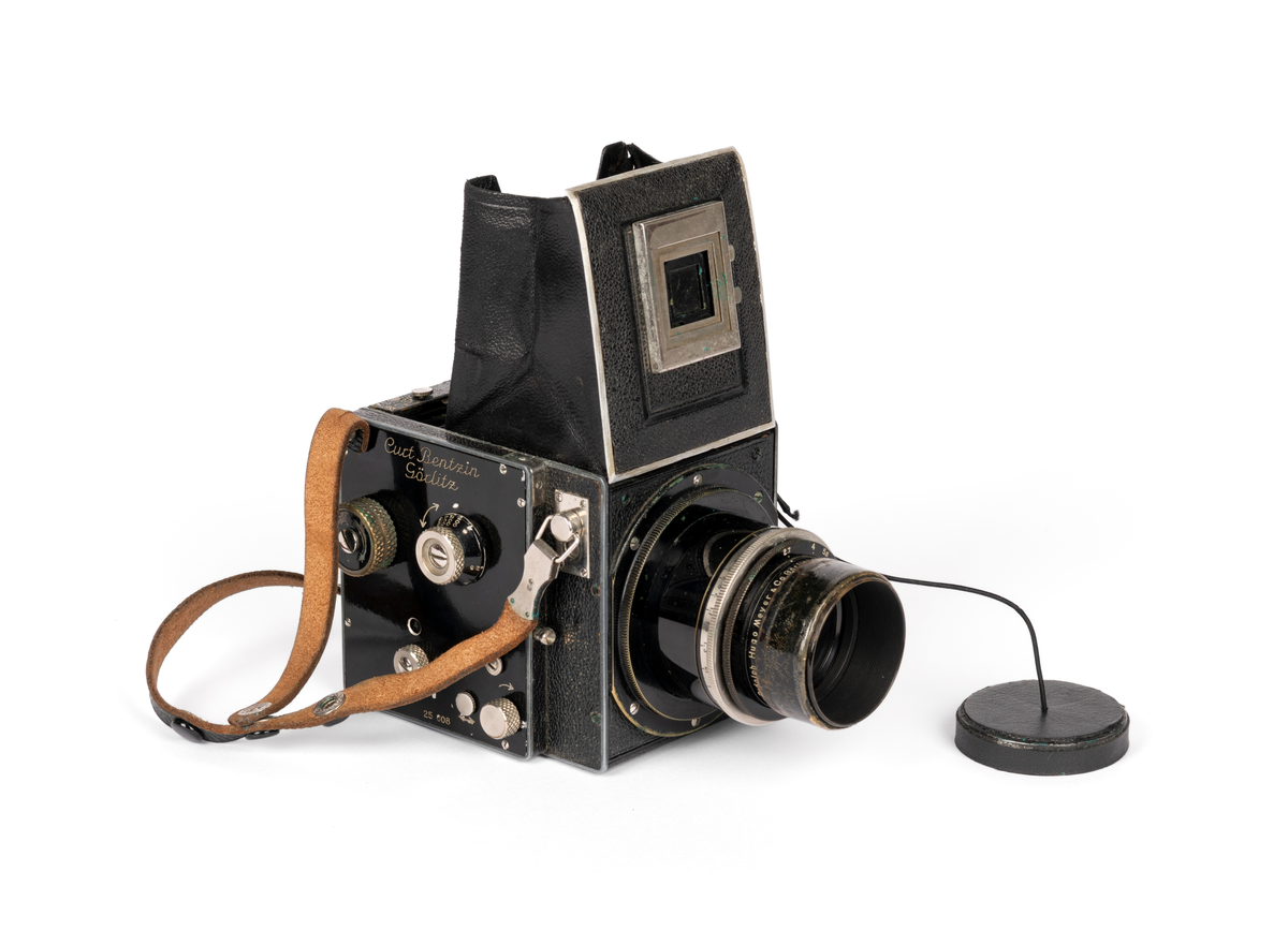 Primarflex 6x6 kamera med polstret skinnveske, bruksanvisning og 2 filter.
Objektiv/ Linse: D.R.P.Dr.Rudolph Hugo Meyer & Co Görlitz Nr. 584973. MakroPlasmat 1:27, f=10.5 cm.

Metallkropp dekt med lær på utsiden. Skinnreim. På toppen en belg som spretter opp ved å trykke på en liten knapp. Ellers flere justeringsknapper på høyre side.
Serienummer: 25608.