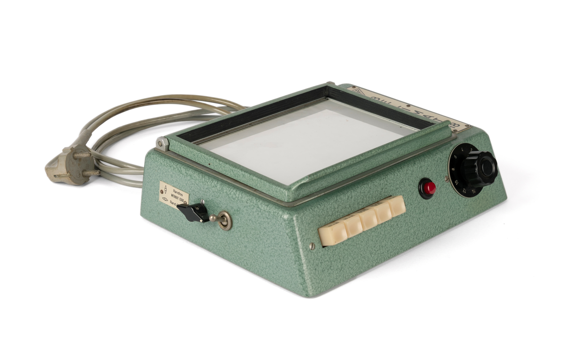 Kontaktkopieringsapparat med to straumfordelarar til prosjektor/ mørkeromslampe. Fleire innstilling- og justeringsknappar. Med tilhøyrande deksel i plast.