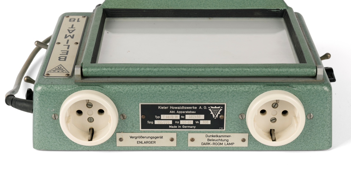 Kontaktkopieringsapparat med to straumfordelarar til prosjektor/ mørkeromslampe. Fleire innstilling- og justeringsknappar. Med tilhøyrande deksel i plast.