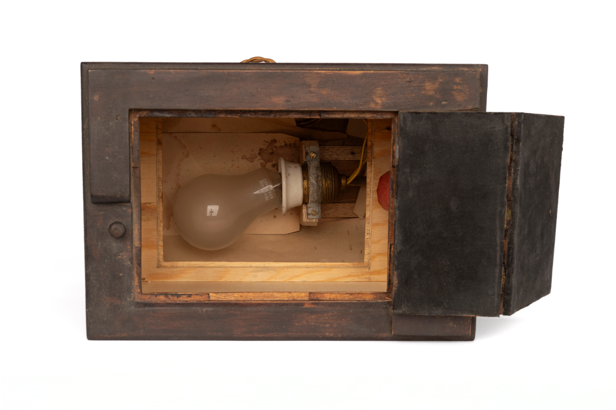 Kontaktkopieringsapparat i tre med lyspære og ledning med utløyserknapp i tre. Brukt av Martin Velle i hans mørkerom. Eldre type som truleg er sjølvlaga.