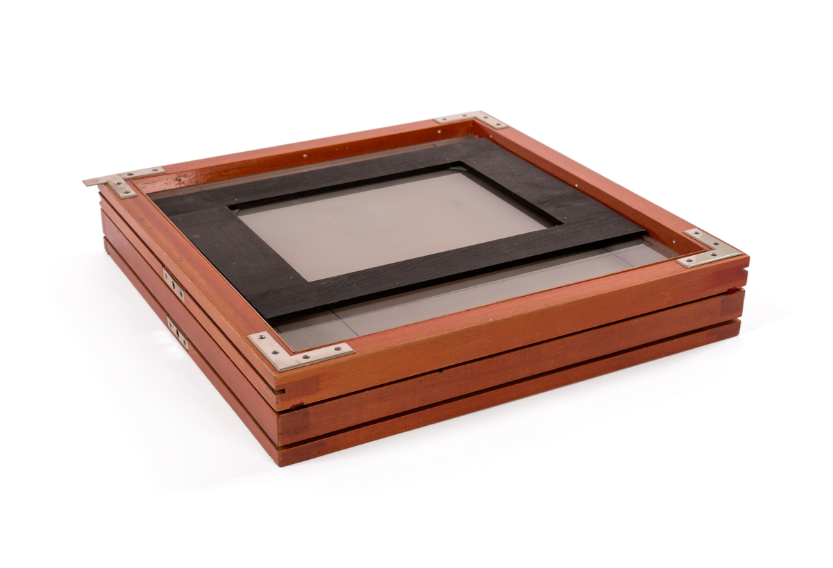 Filmkassett tilhørende atelierkamera. 17x23cm negativ planfilm/glas. Med glasplate til å stille skarpt.