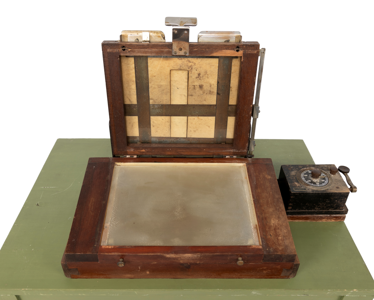 Kontaktkopieringsapparat brukt av Martin Velle i hans mørkerom. Apparatet er montert på eit bord med innebygd lampe og eit tidsur.