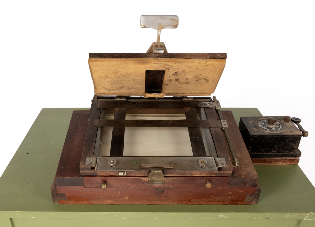 Kontaktkopieringsapparat brukt av Martin Velle i hans mørkerom. Apparatet er montert på eit bord med innebygd lampe og eit tidsur.