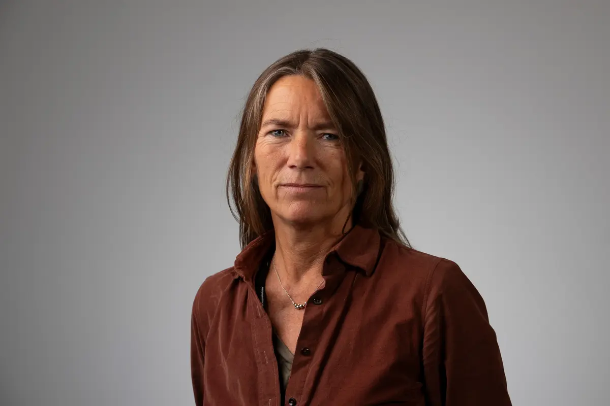 Portrett av en kvinne med langt, mørkt hår og brun bluse