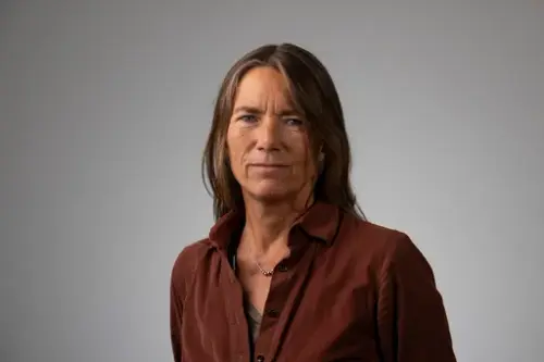 Portrett av en kvinne med langt, mørkt hår og brun bluse