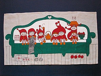 Textiltryckt julbonad på grov ljus linnebotten. Motiv med sju tomtar som sitter på en stor grön soffa, med paket, kaffekittel och äpplen runt sig.
 Trykt med starka, klara färger med tunna svarta konturer. Fållad runt om på maskin.