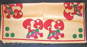 Textiltryckt julgransmatta på oblekt juteväv. Ofållad på två sidor, stadkant på två sidor. Motiv med ett par tomtar som dansar, återkommer två par på varje sida. 16 mm röd rand som ram 1310 X 1315 mm. Tre stora gröna klot i varje hörn.