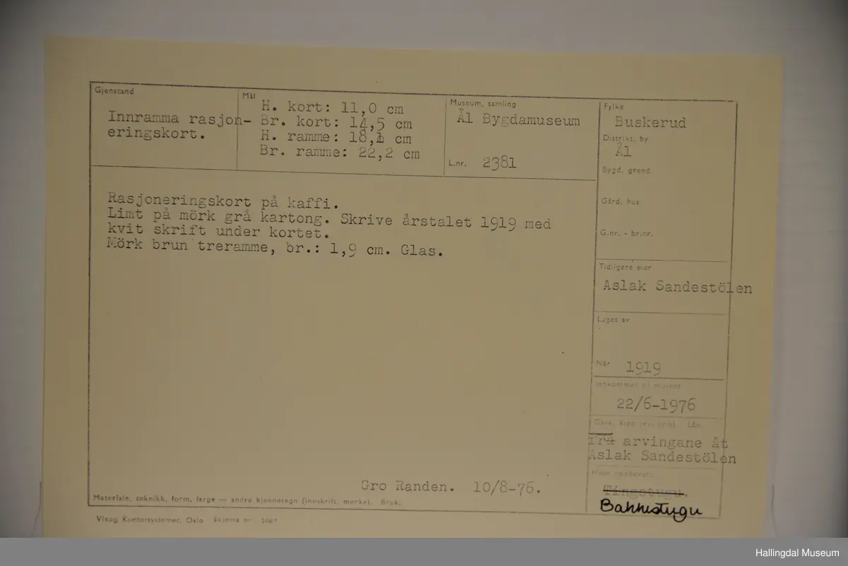 Rasjoneringskort til kaffi. Limt på mørk grå kartong. Skrive årstalet 1919 med kvit skrift under kortet. Mørk brun treramme.