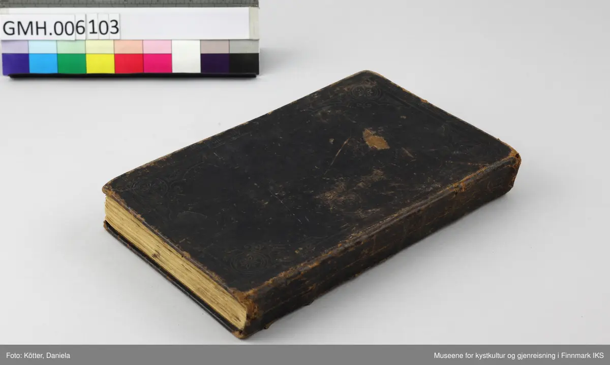 Det nye testamente på nordsamisk, utgitt 1895 i Kristiania. Boka har omslag av mørkebrunt skinn. På for- og baksiden er det innpreget ornamentrammer. På forsiden er det i tillegg preget inn et kors. På bokryggen er det preget inn tittelen "Ođđa Testamenta" og to ornamentbånd. Begge elementer viser rester etter forgylling. Bindingen er utført med tråd.  Det er innskrevet forskjellige navn. På første side står det Mauritz og et etternavn som er vanskelig å tyde. På siste side står det, i tillegg til noen regnestykker som er skrevet opp ned på sida, navnet «Ellen Marie Martensen» samt Sletten, som kan tilhøre familienavnet eller tyde på et sted, slik som inskripsjon "Pallklubben". Bibelen stammer fra samme dødsbo som brevet og bilder fra Emilie Andersen i aksesjon GMH2025-002.