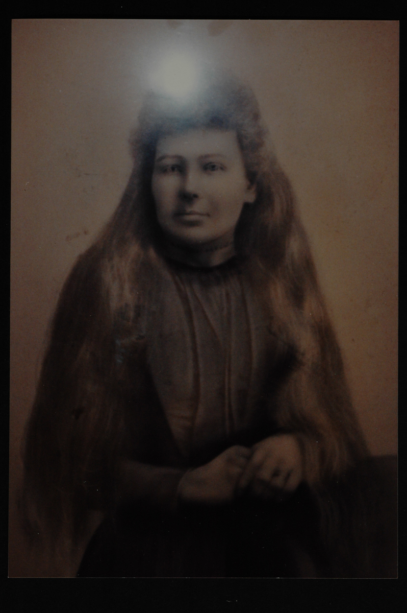 Tegnet portrett av en kvinne med langt, utslått hår. Blits-flekk øverst på bildet. 