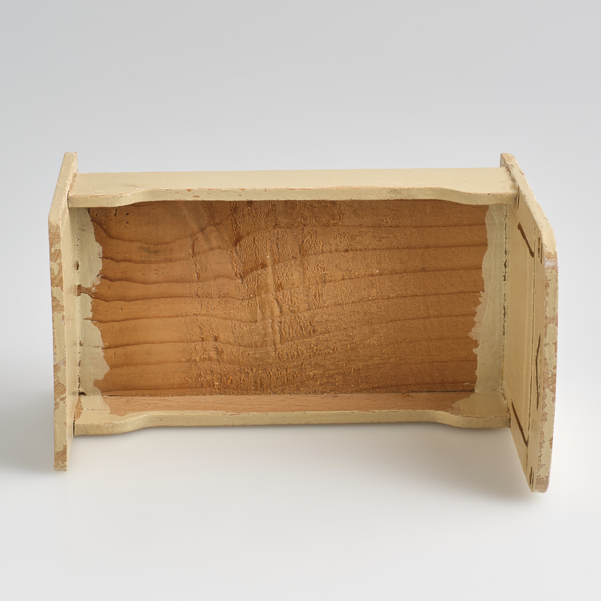 Leketøysseng til dukkehus, tilhørt en lekestue på 1930-tallet.
Sengen består av tre individuelle løse deler; sengeramme, pute og dyne.
Sengerammen er av tre, malt kremhvit, og limt sammen av 5 deler; to endesider, to sengekanter, og en plate. 
Endesiden ved sengens hodeende, er dekorert med et inngravert mønster malt i gull, mønsteret er bygd opp av en trekant øverst i midten, med to korte streker over hverandre på begge sider ut mot kanten, og en større firkant under, uten understrek. Endesiden i fotenden er noe lavere enn ved hodeenden, og dekorert på tilsvarende måte på utsiden. Kantene langs sengen er skjært ut rette, med forhøyning mot endesidene. Alle delene er limt rundt platen som utgjør bunnen av sengen. På undersiden av platen er det skrevet inn en strek med et seks-tall på hver side, med blyant.
Puten er sydd sammen av et lysegrønt stoff, dekorert med et blonde-bånd som streker seg over ca. midten av puten. Puten er generelt preget av misfargin.
Dynen er sydd sammen av et blått blomster-dekorert stoff, og pyntet med samme blonde-bånd som strekker seg over topp-delen av dynen. Formmessig er dynen tilsvarende rektangulær, med en avrundet ende i fotenden.