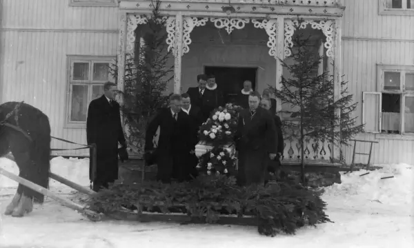 Menn som bærer kiste ut på hesteslede med granbar