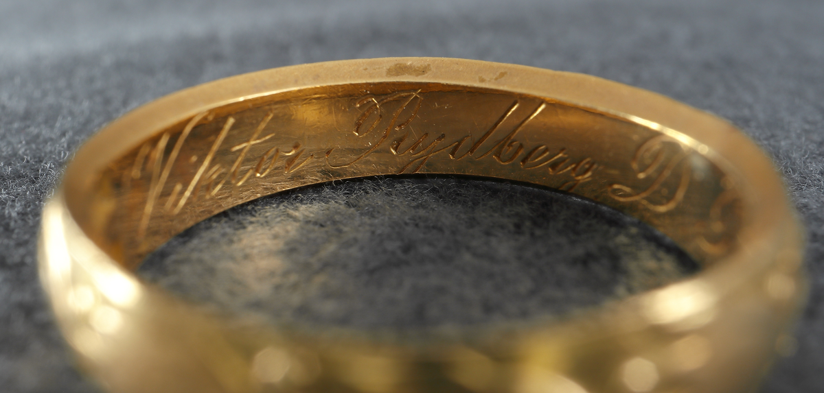 Doktorsring av guld med lagerkransmönster. Tillhört Viktor Rydberg. Ringen har utvändigt ett lagerkransmönster. Invändigt har den texten "Viktor Rydberg D. Phil. Honor 18 6/9 77". Den är försedd med stämplar, kontrollstämpel, 20K, stadsstämpel (Växjö), mästarstämpel (EEH) och årtalsstämpel Y5 (1877).
Inskrivet i huvudbok 1984.