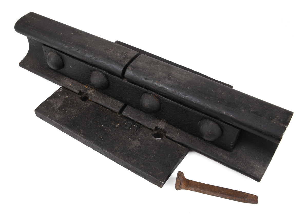 Rälsskarv (:2) av järn med underläggsplatta (:3) samt rälsspik (:4).