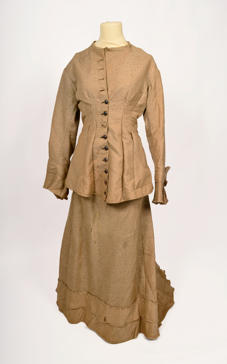 drakt. Fotvidt skjørt. Vid jakke. Fihursydd. Beige mønstret. Kappe på skjørt. Sløyfer på ermer.