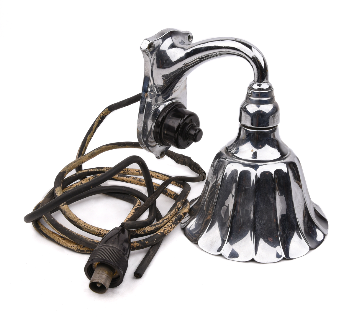 Elektrisk armatur av metall. Troligen modell nr 3050 (SJ typ X), tillverkad av Bröderna Malmströms Metallvarufabrik.
Beskrivning från deras katalog över Järnvägsarmaturer från 1934:
"Fästplattans höjd 160 mm, största bredd 80 mm. Största avstånd från väggen 230 mm. Utföres i gjuten mässing. Skärmen av mässingsplåt, 155 mm diam., invändigt vitlackerad. Lamphållaren är av samma konstruktion som hos n:r 3035, således Edisongänga och fjädrande bottenkontakt. Avsedd för max. 40 volt. Strömbrytaren av typ "Membra". Kan även levereras med normal bajonettlamphållare."