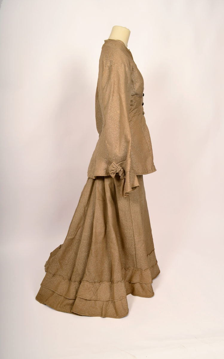 drakt. Fotvidt skjørt. Vid jakke. Fihursydd. Beige mønstret. Kappe på skjørt. Sløyfer på ermer.