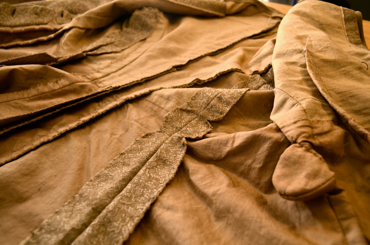 drakt. Fotvidt skjørt. Vid jakke. Fihursydd. Beige mønstret. Kappe på skjørt. Sløyfer på ermer.