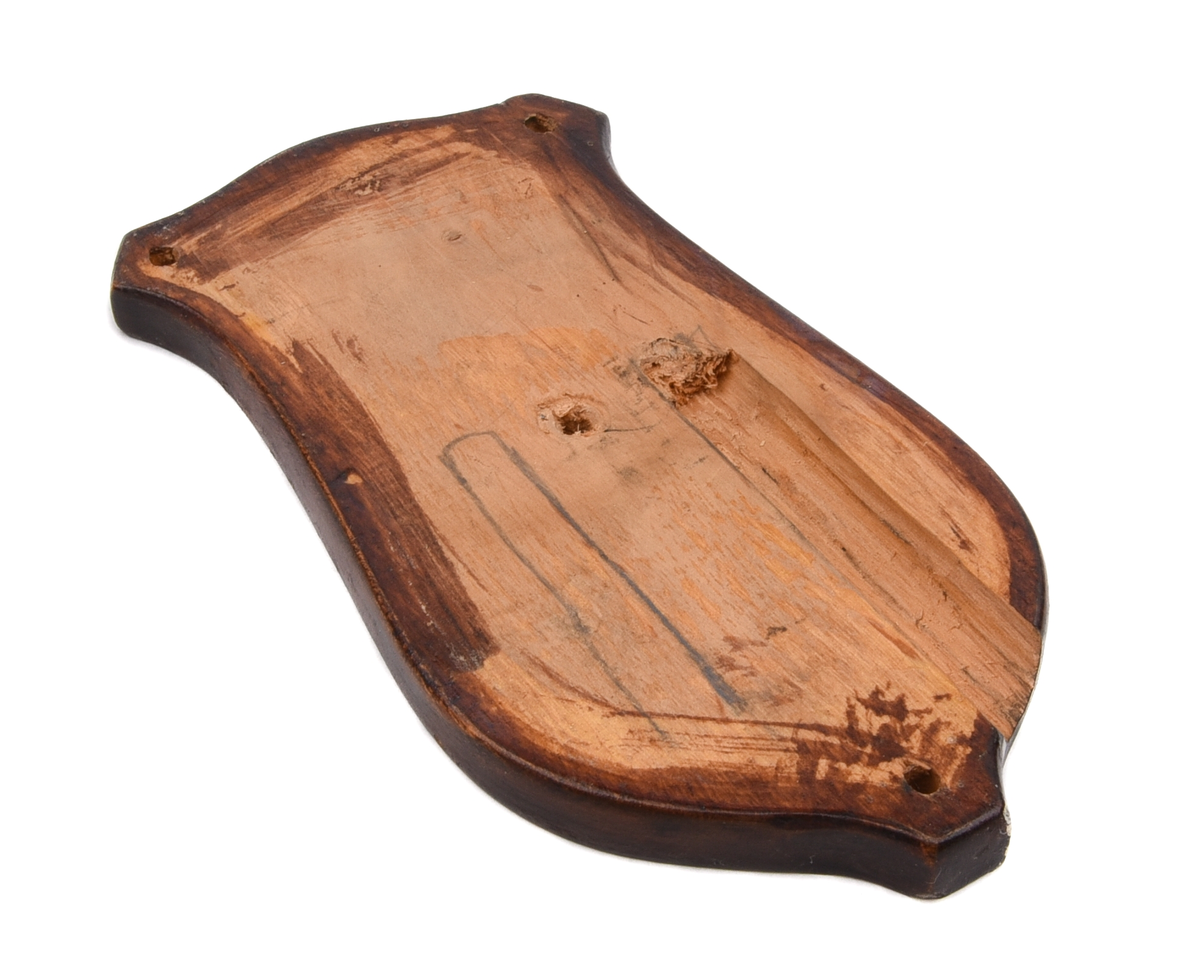 Elektrisk armatur av metall. Troligen modell nr 3050 (SJ typ X), tillverkad av Bröderna Malmströms Metallvarufabrik.
Beskrivning från deras katalog över Järnvägsarmaturer från 1934:
"Fästplattans höjd 160 mm, största bredd 80 mm. Största avstånd från väggen 230 mm. Utföres i gjuten mässing. Skärmen av mässingsplåt, 155 mm diam., invändigt vitlackerad. Lamphållaren är av samma konstruktion som hos n:r 3035, således Edisongänga och fjädrande bottenkontakt. Avsedd för max. 40 volt. Strömbrytaren av typ "Membra". Kan även levereras med normal bajonettlamphållare."