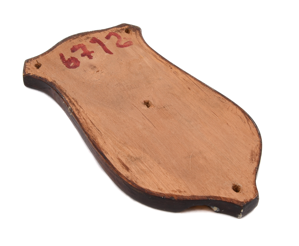 Elektrisk armatur av metall. Troligen modell nr 3050 (SJ typ X), tillverkad av Bröderna Malmströms Metallvarufabrik.
Beskrivning från deras katalog över Järnvägsarmaturer från 1934:
"Fästplattans höjd 160 mm, största bredd 80 mm. Största avstånd från väggen 230 mm. Utföres i gjuten mässing. Skärmen av mässingsplåt, 155 mm diam., invändigt vitlackerad. Lamphållaren är av samma konstruktion som hos n:r 3035, således Edisongänga och fjädrande bottenkontakt. Avsedd för max. 40 volt. Strömbrytaren av typ "Membra". Kan även levereras med normal bajonettlamphållare."