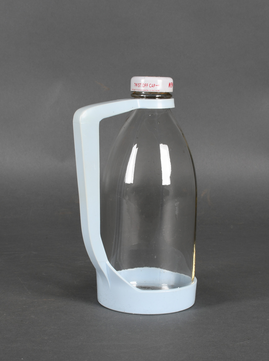 Flaske i klart glass, med lyseblå plastholder og hvit plastkork med rød tekst.