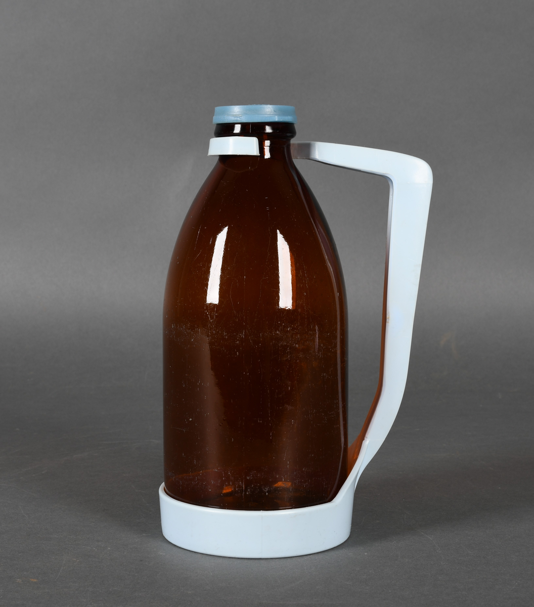 Flaske i brunt glass, med lyseblå plastholder og mellomblå plastkork.