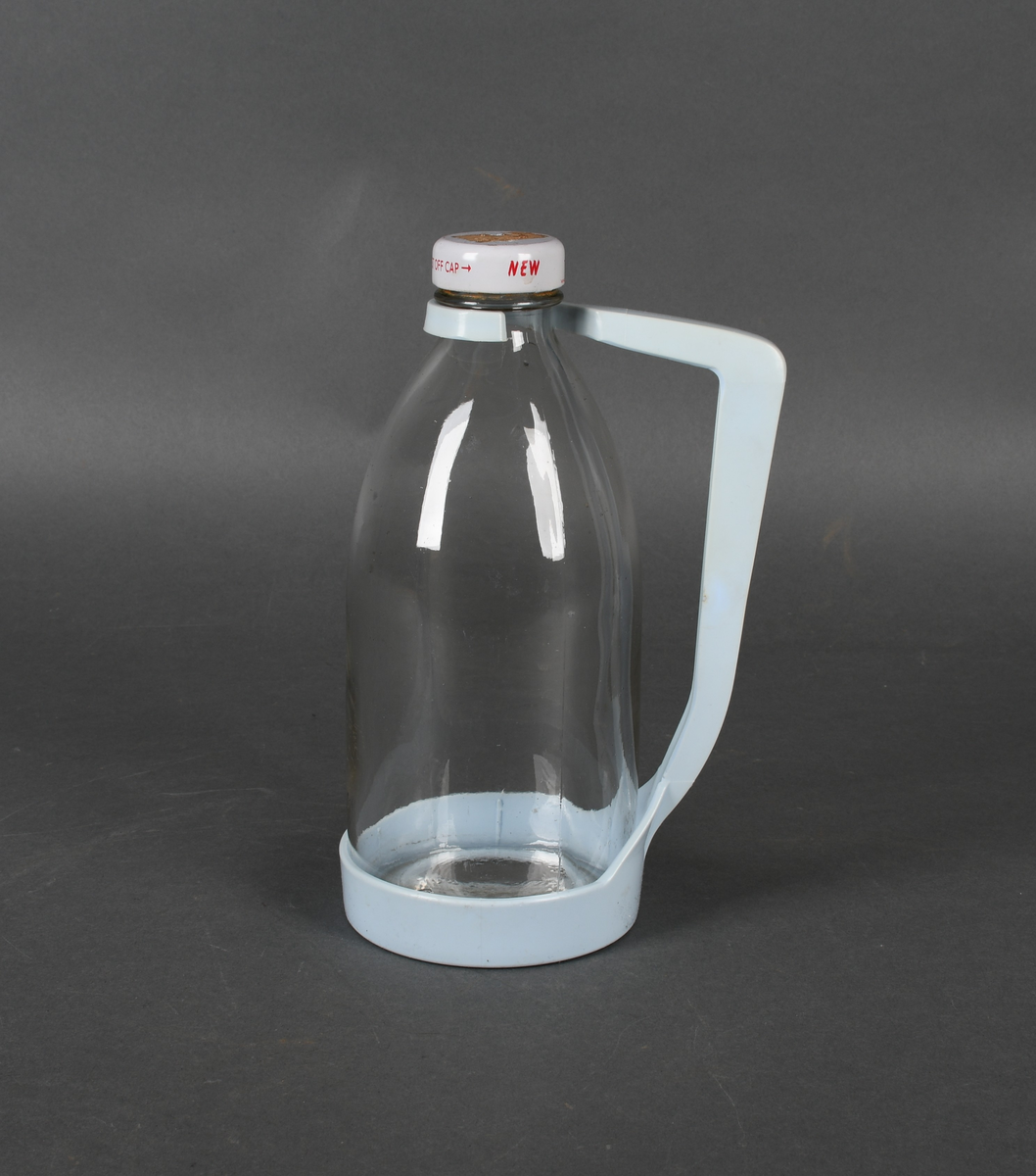 Flaske i klart glass, med lyseblå plastholder og hvit plastkork med rød tekst.