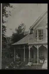 Murhus med to etasjer og forseggjort balkong og veranda. En 