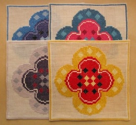 Fyra fyrkantiga dukar, broderade i korsstygn på blekt linnebotten. Broderad i olika 
färgställningar: gul/röd, grå/lila, blågrön/rosa och blå/lila lingarn. Ram 2 mm från kanten med en rad korsstygn. Motiv av fyrflikig blomma. 

Originalmönster, kalkyl och skiss och broderiprov finns.

Se också stor duk KLH.A3:787a.