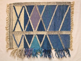 Mattprovet är vävt i rölakansteknik.
Mönstret består i grå diagonal ränder i ett rut mönster
på en blå botten.

Mönsterskiss finns KLh.D3:526 b

Mattprovet är vävt på Önnestads mattväveri