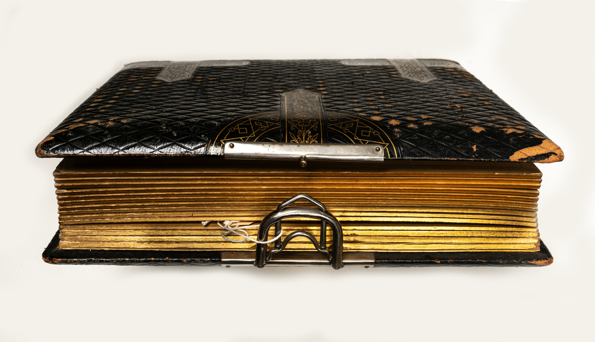 Fotoalbum, brunt skinn. "Beslagsornamentik" i relief, lås.