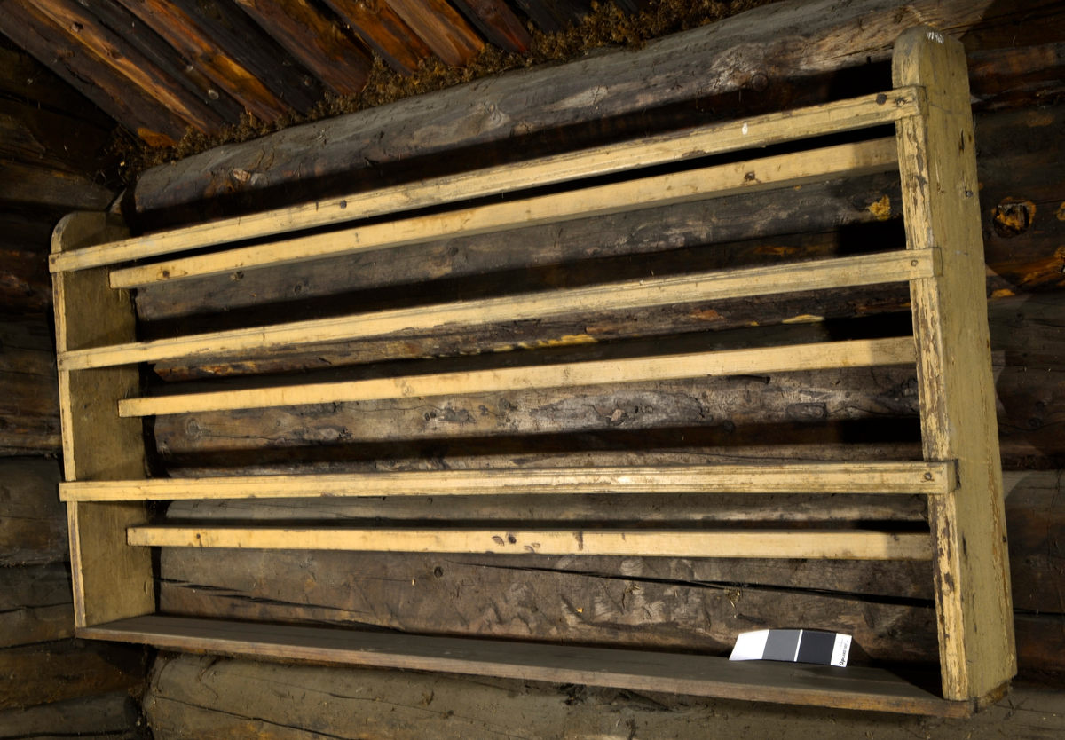 Tallerkenrekke med hylle nederst.