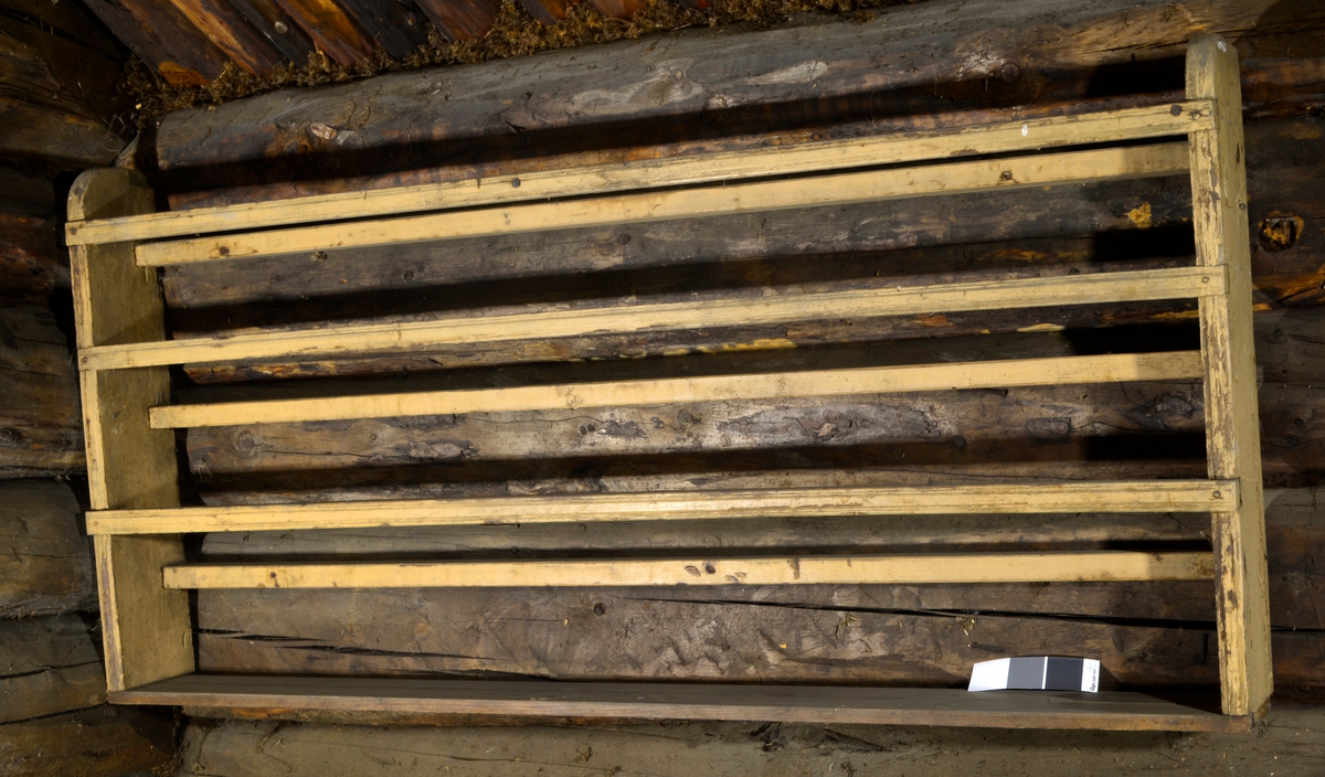 Tallerkenrekke med hylle nederst.