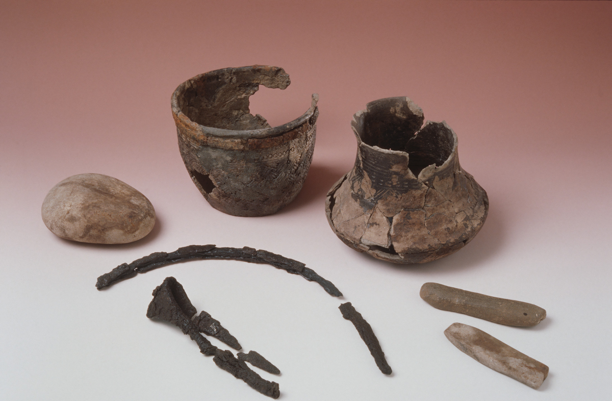 "Kvartsittbryne, avbrukket i den ene ende. Lengde 10 cm, bredde 3 cm, tykkelse 1,1 cm."  Ny beskrivelse etter revisjon: Endefragment av bryne av grå kvartsitt, stl.: 101 mm, br.: 18-29 mm, t.: 10-12 mm. 