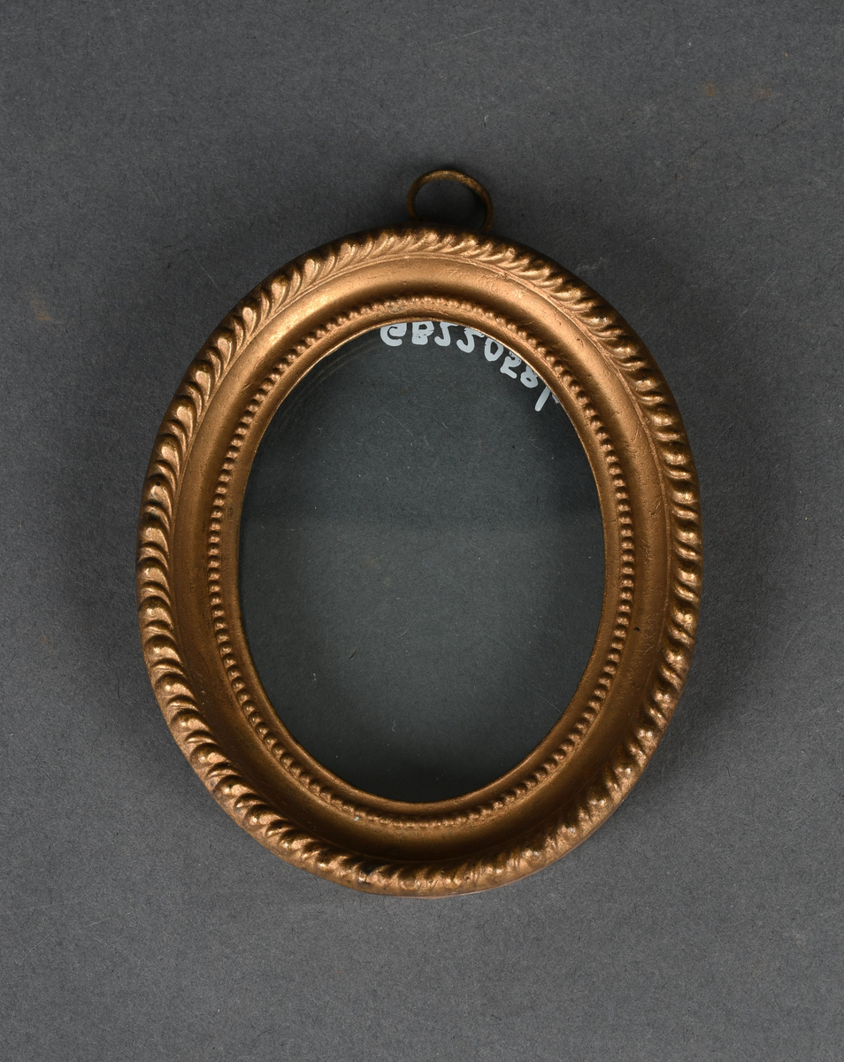 Oval bilderamme med treramme og gullmalt, profilert metallkant med to perlerader. Rammen har et løst, beskyttende glass og en ring festet til øvre kant.