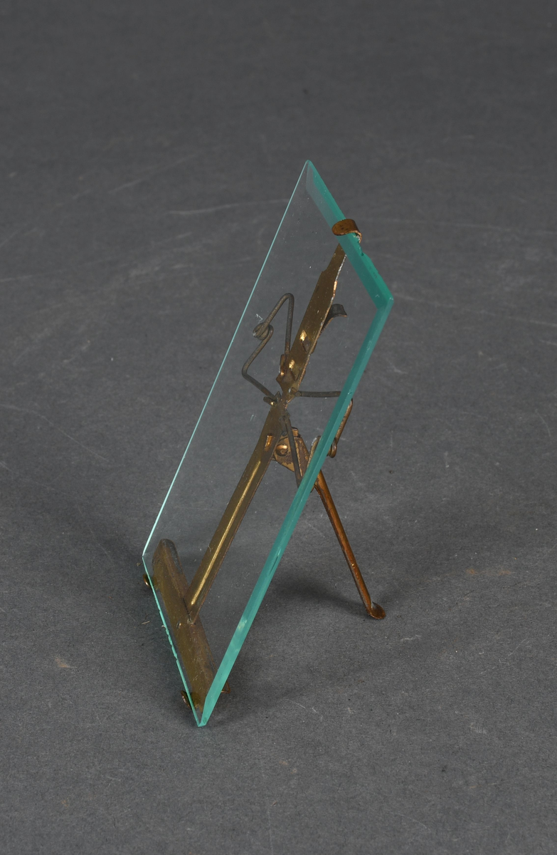 Stående, rektangulær bilderamme i form av en glassplate med et metallstativ på baksiden.
