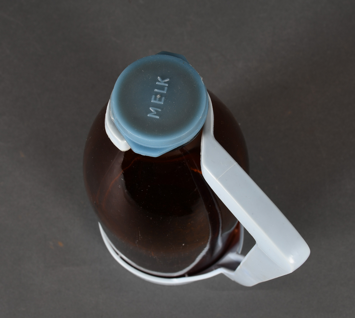 Flaske i brunt glass, med lyseblå plastholder og mellomblå plastkork.