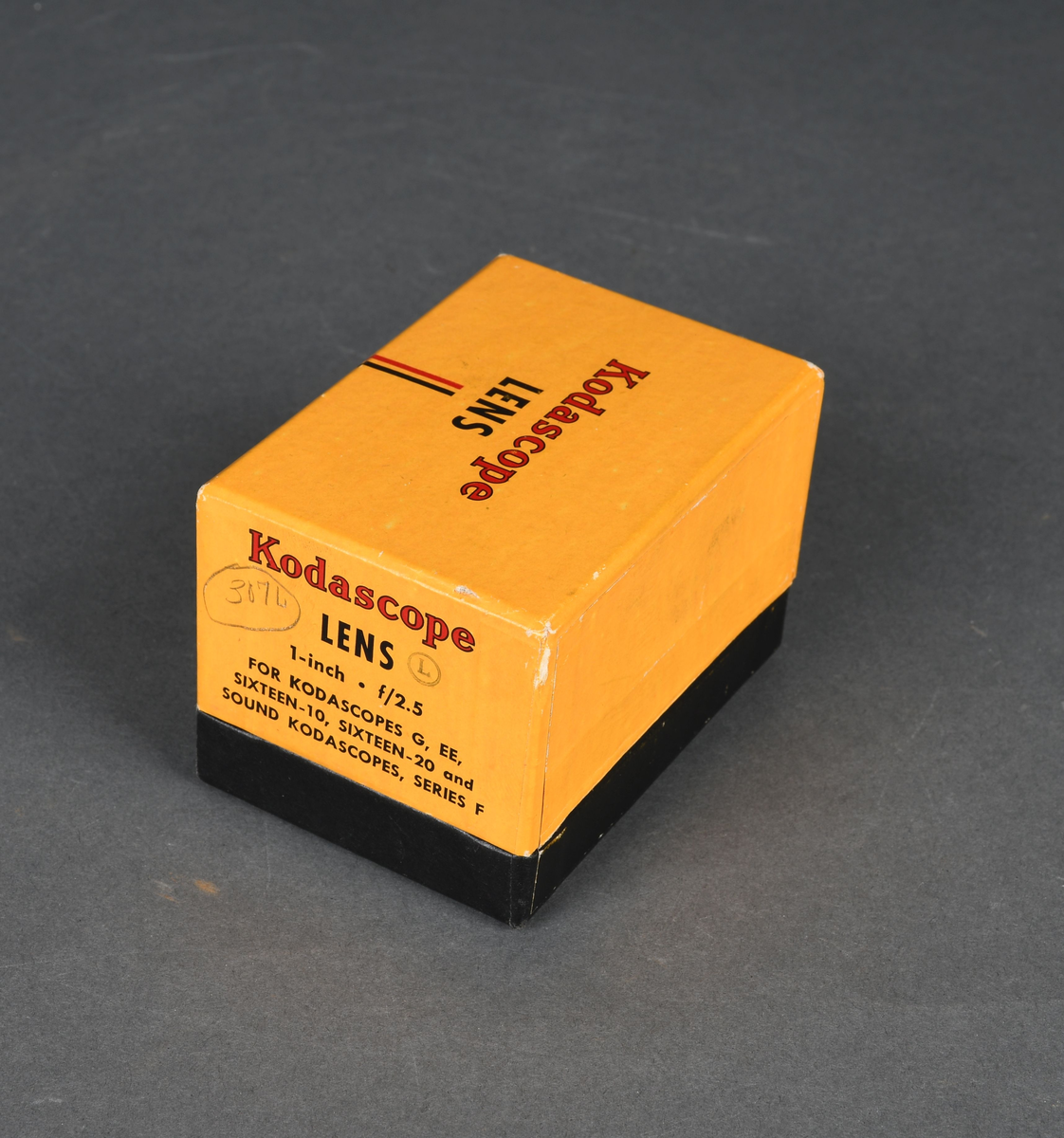 Linse til filmkamera i pappeske med hengslet lokk.