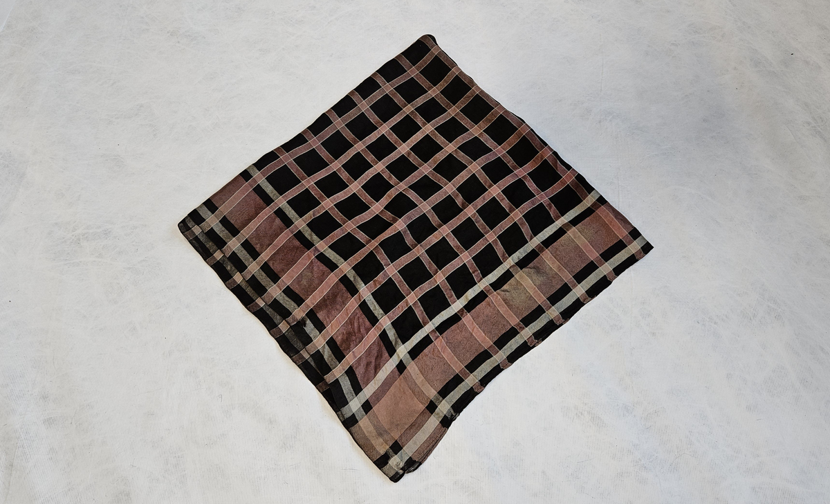 Tørkleet har ruter i rosa og hvitt og er kvadratisk i fasongen. Typen tyder på en høyere alder enn fra 1863. Det er trolig et arvestykke som den tidligere eieren har fått.