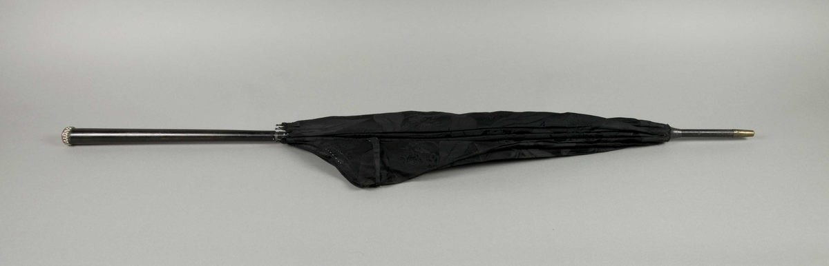 Dameparaply med sort silketrekk, metallspiler, trestang og på enden av håndtaket en liten metallholk.