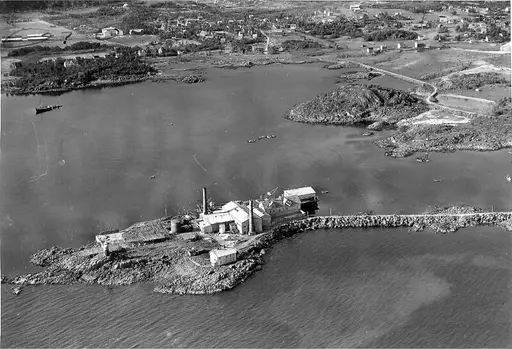 Flybilde: Neptun Sildoljefabrikk i 1956. Melbu i bakgrunnen. Deler av anlegget brant ned i 1946. I 1956 var fremdeles deler av driften ute under åpen himmel.