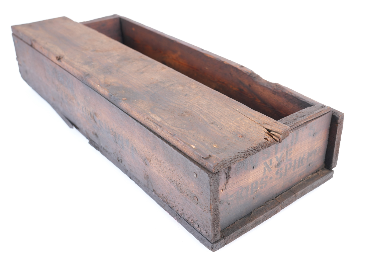 Trekasse fylt med 284 store spikar. På kassa er det trykt tekst. Oppsida av kassa er halvt ope, slik at øvre halvdelen av spikrane er synlege. Spikrane er like: Hovudet meir ovalt enn rundt, og litt kantete. Sjølve spikaren har fire sider og smalnar inn nedst. To av sidane er breiare enn dei to andre.