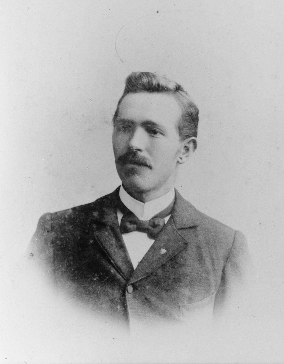 Portrett av en mann med bart og sløyfe i halsen. 