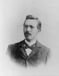 Portrett av en mann med bart og sløyfe i halsen.