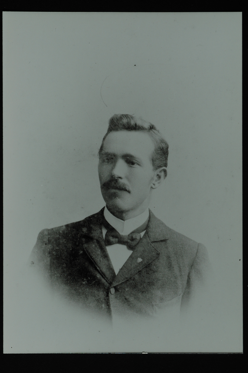 Portrett av en mann med bart og sløyfe i halsen. 