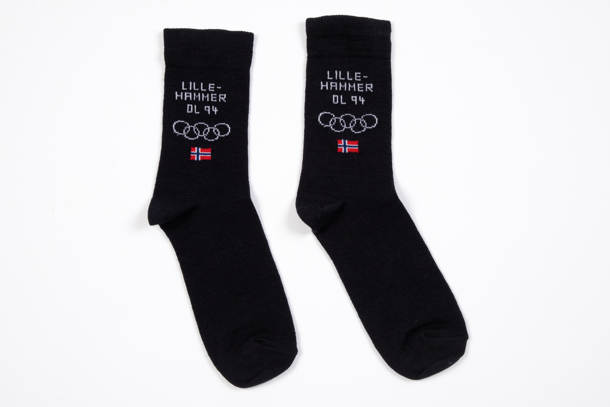 Et par sokker strikket i mørkeblått ullgarn. Innstrikket på begge sider med hvitt LILLEHAMMER OL, de olympiske ringer, samt norsk flagg i farger.